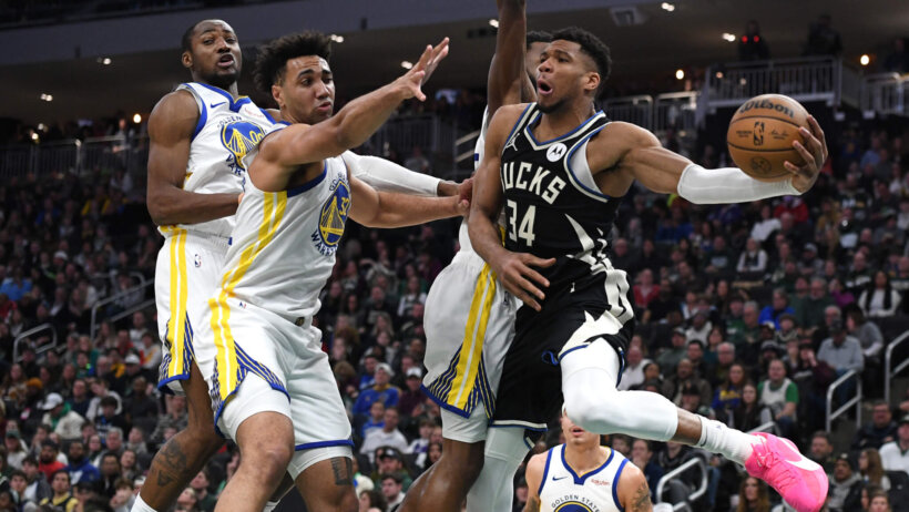 Milwaukee Bucks forward Giannis Antetokounmpo tries to pass around two Golden State Warriors