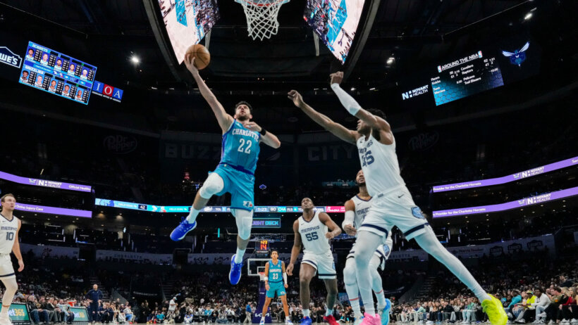 Charlotte Hornets guard Vasilije Micic attempts a layup on a hoop guarded by Memphis Grizzlies forward Brandon Clarke.