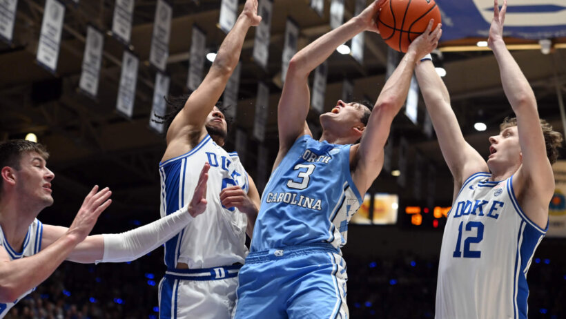 North Carolina player shooting over Duke defenders