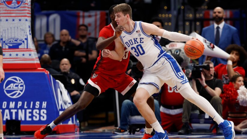 Duke Blue Devils basketball player Kyle Filipowski dribbles a basketball while being defended by NC State Wolfpack player Mohammed Diarra.