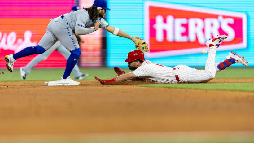 Philadelphia Phillies designated hitter Kyle Schwarber slides into second base as Toronto Blue Jays shortstop Bo Bichette tries to tag him out