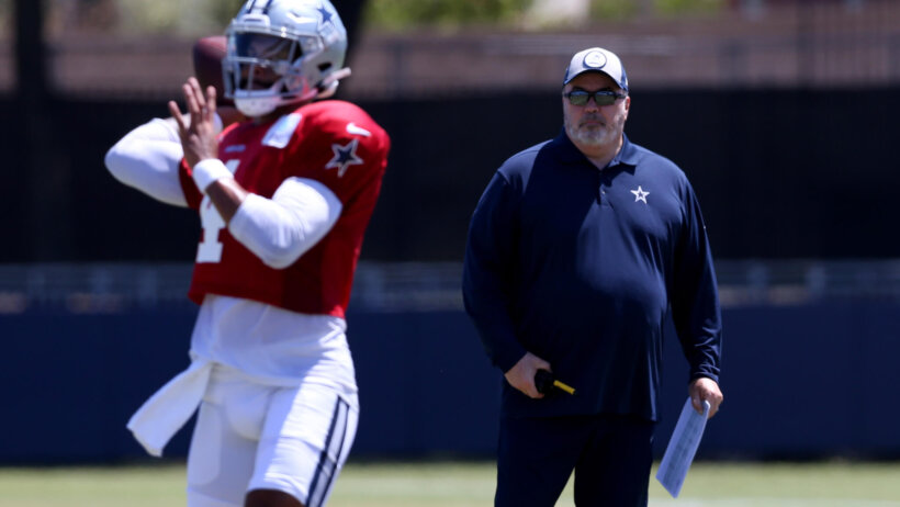Dak Prescott throwing a pass in practice as Mike McCarthy looks on